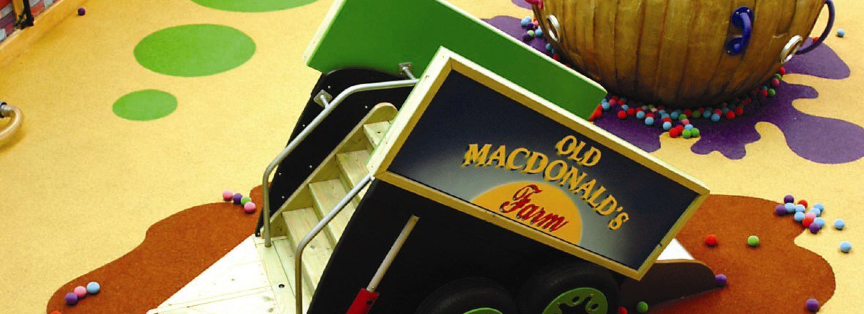 A indoor playground designed to look like a farm with a close up of a truck as a slide.
