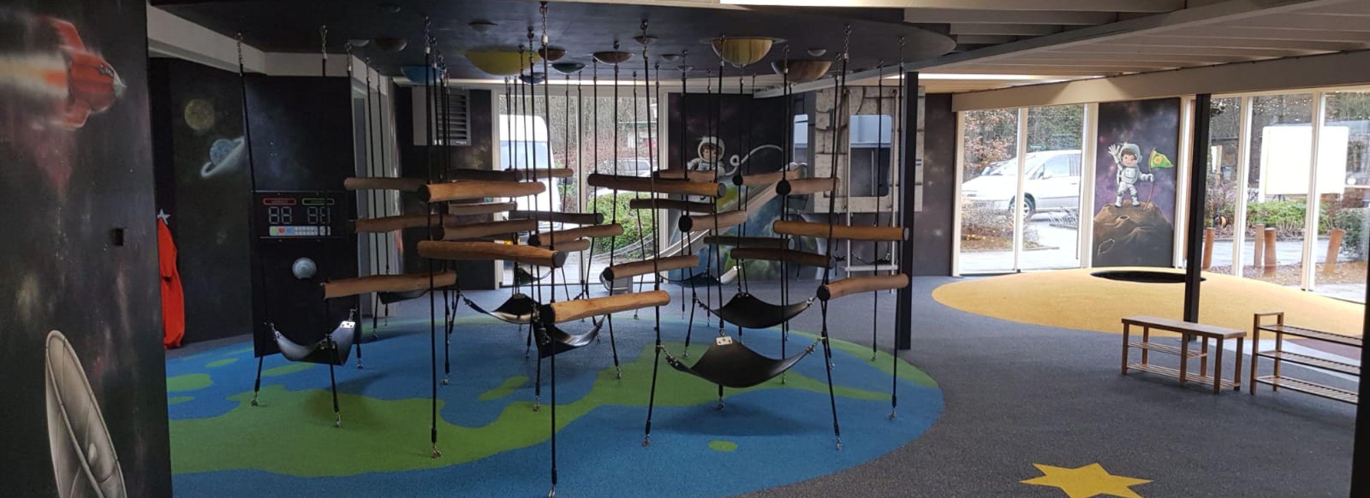 Indoor playground with rubber flooring and a climbing frame.